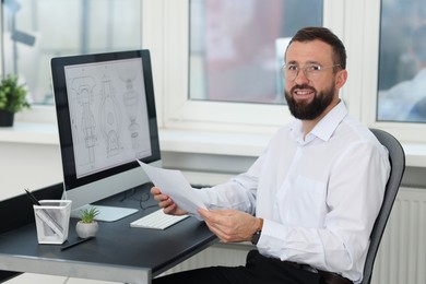 Photo of Technician making digital engineering drawing on computer at desk in office