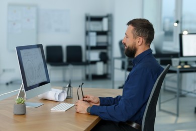 Photo of Technician making digital engineering drawing on computer at desk in office