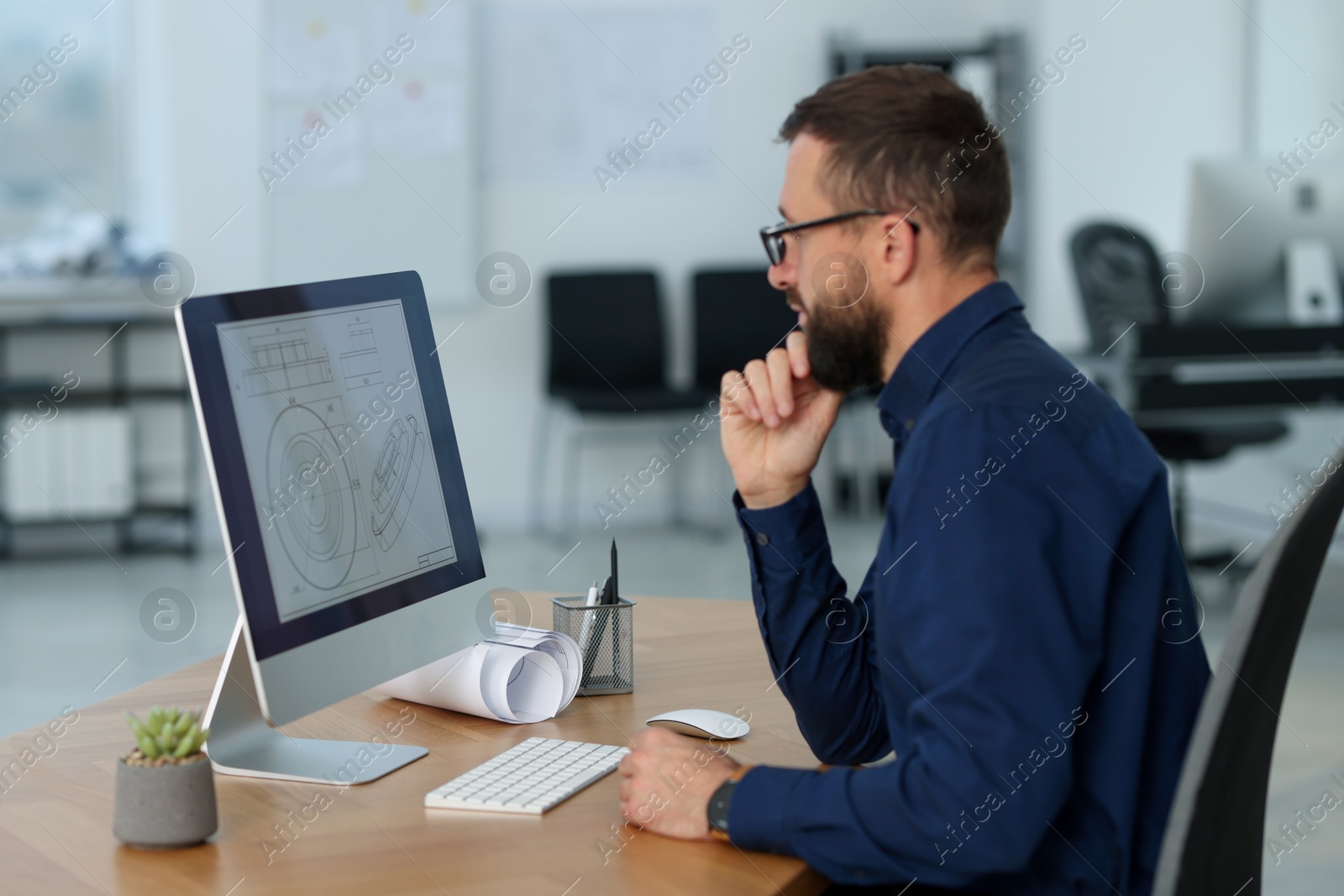 Photo of Technician making digital engineering drawing on computer at desk in office