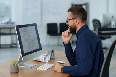 Photo of Technician making digital engineering drawing on computer at desk in office