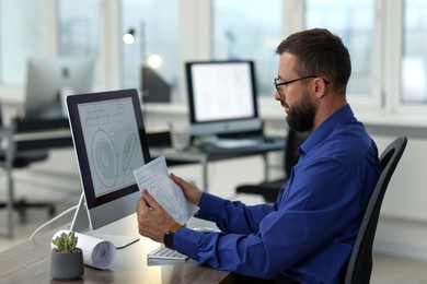 Photo of Technician making digital engineering drawing on computer at desk in office