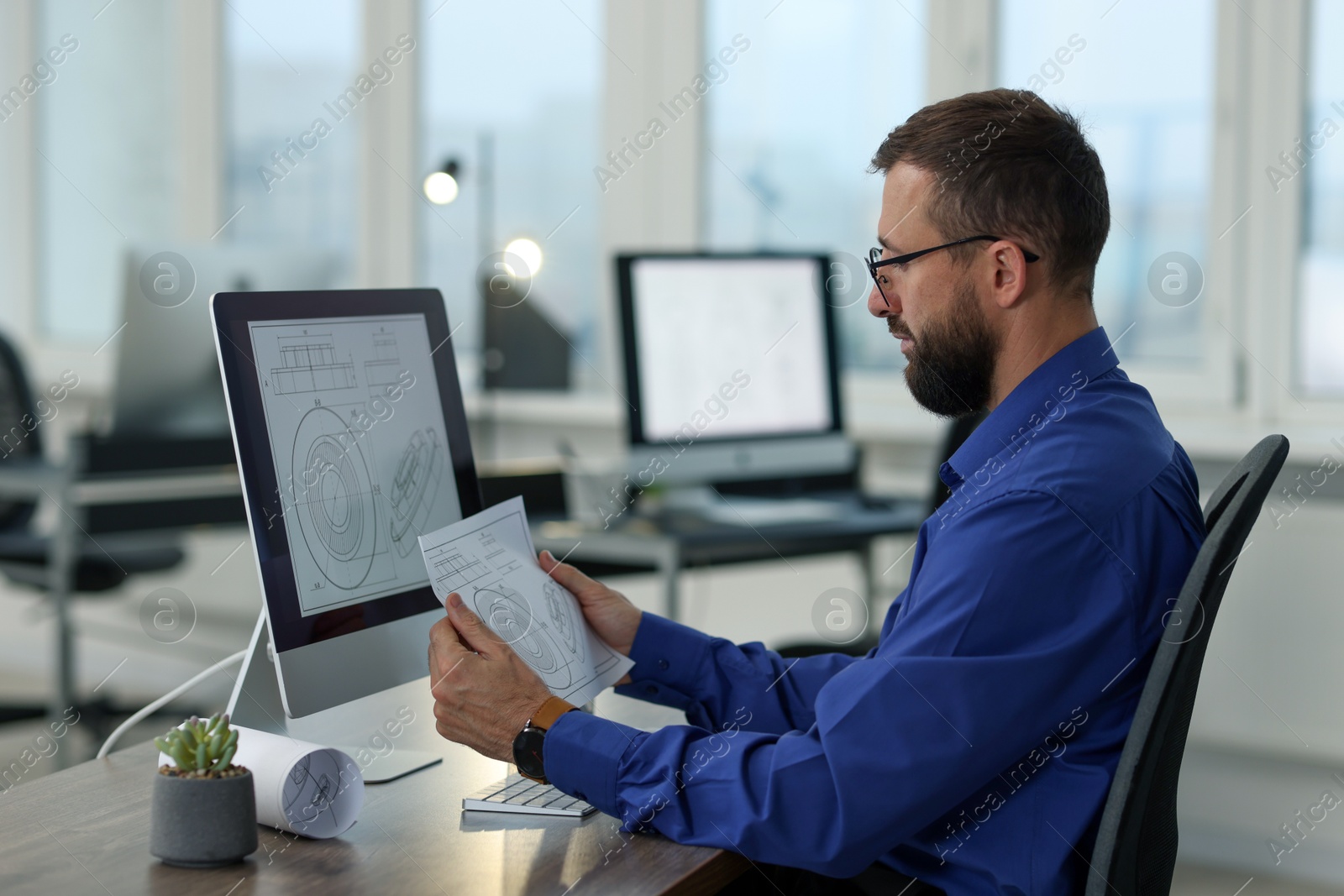 Photo of Technician making digital engineering drawing on computer at desk in office