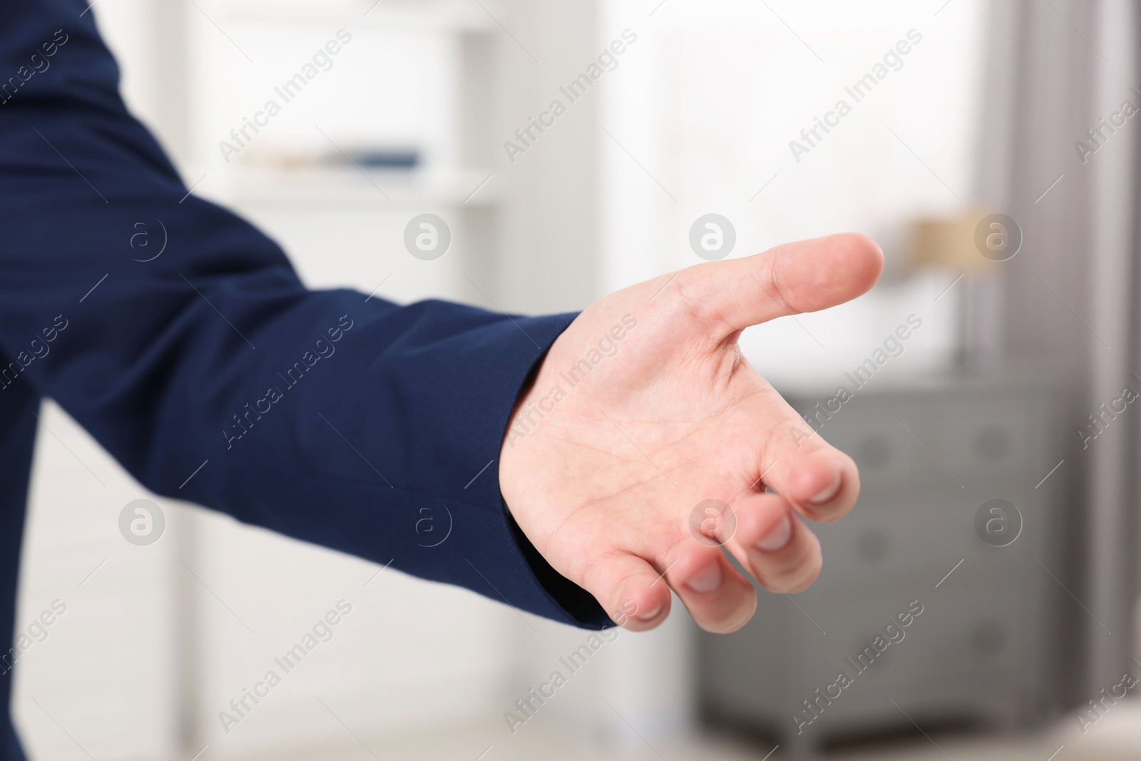 Photo of Offering help. Man reaching his hand indoors, closeup