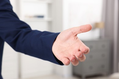 Photo of Offering help. Man reaching his hand indoors, closeup