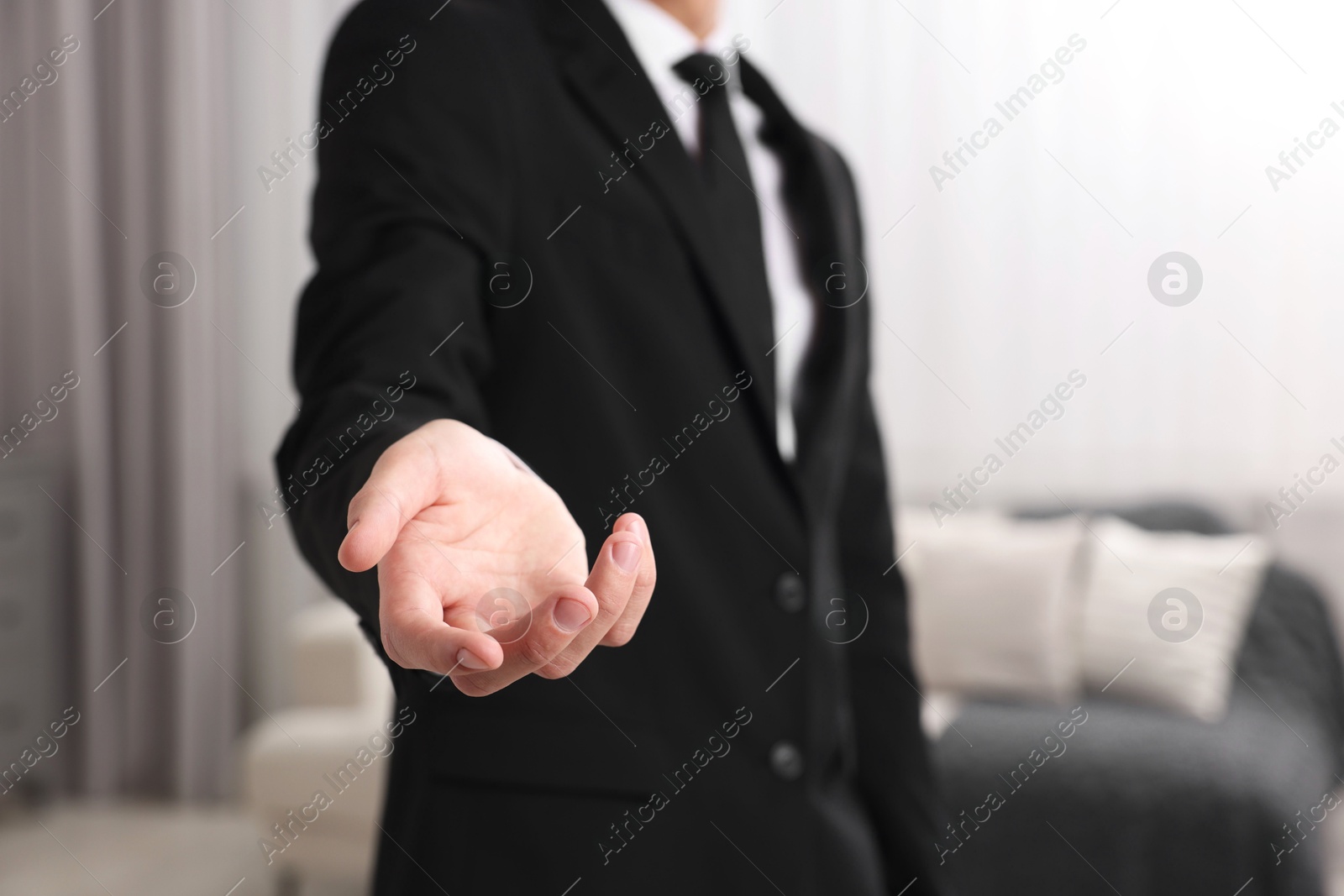 Photo of Offering help. Man reaching his hand indoors, closeup