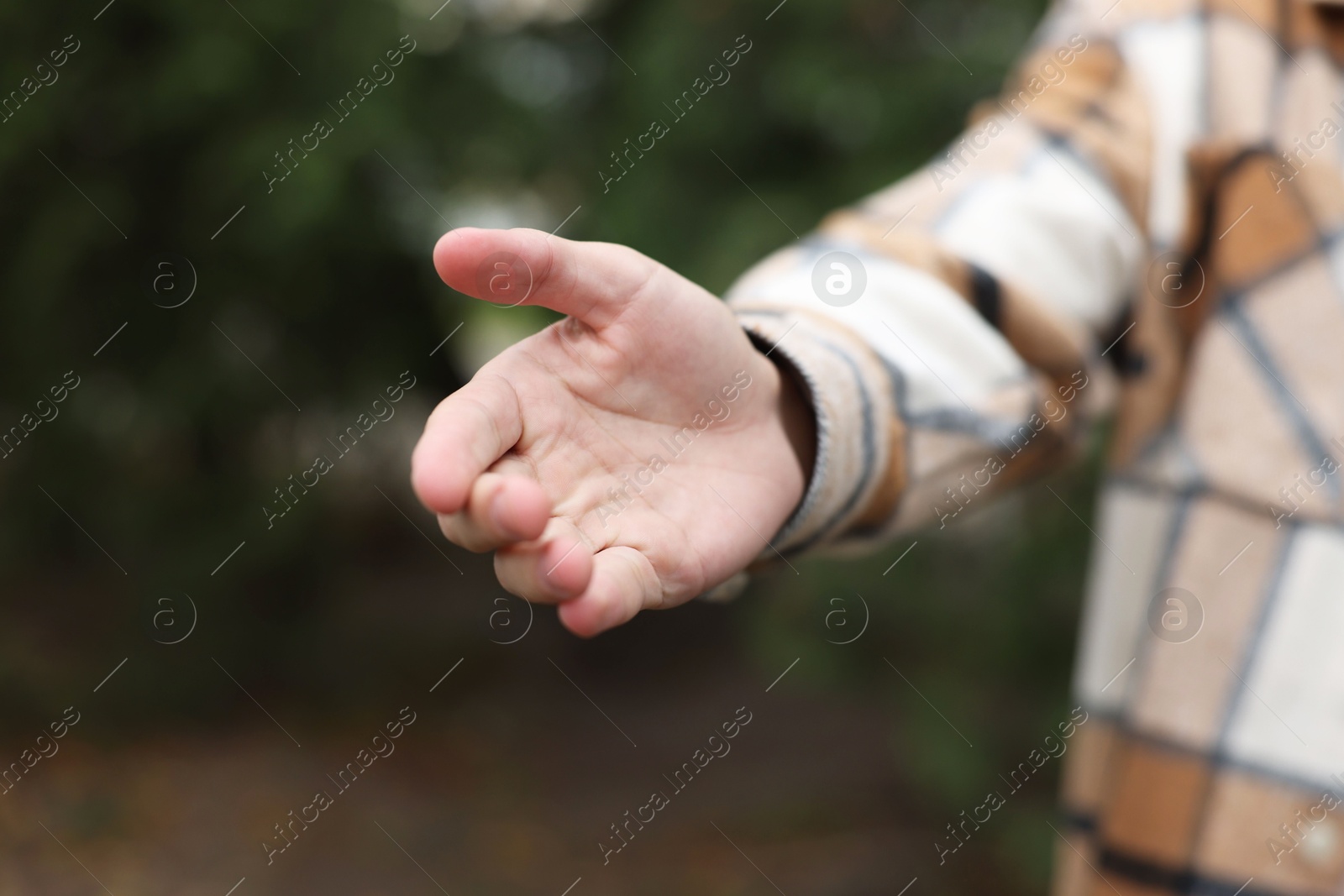 Photo of Offering help. Man reaching his hand outdoors, closeup