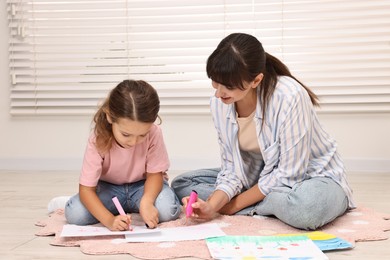 Autism therapy. Smiling psychologist and little girl drawing pictures in mental health center