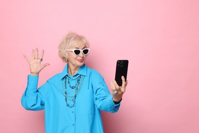 Cool grandmother taking selfie on pink background. Space for text