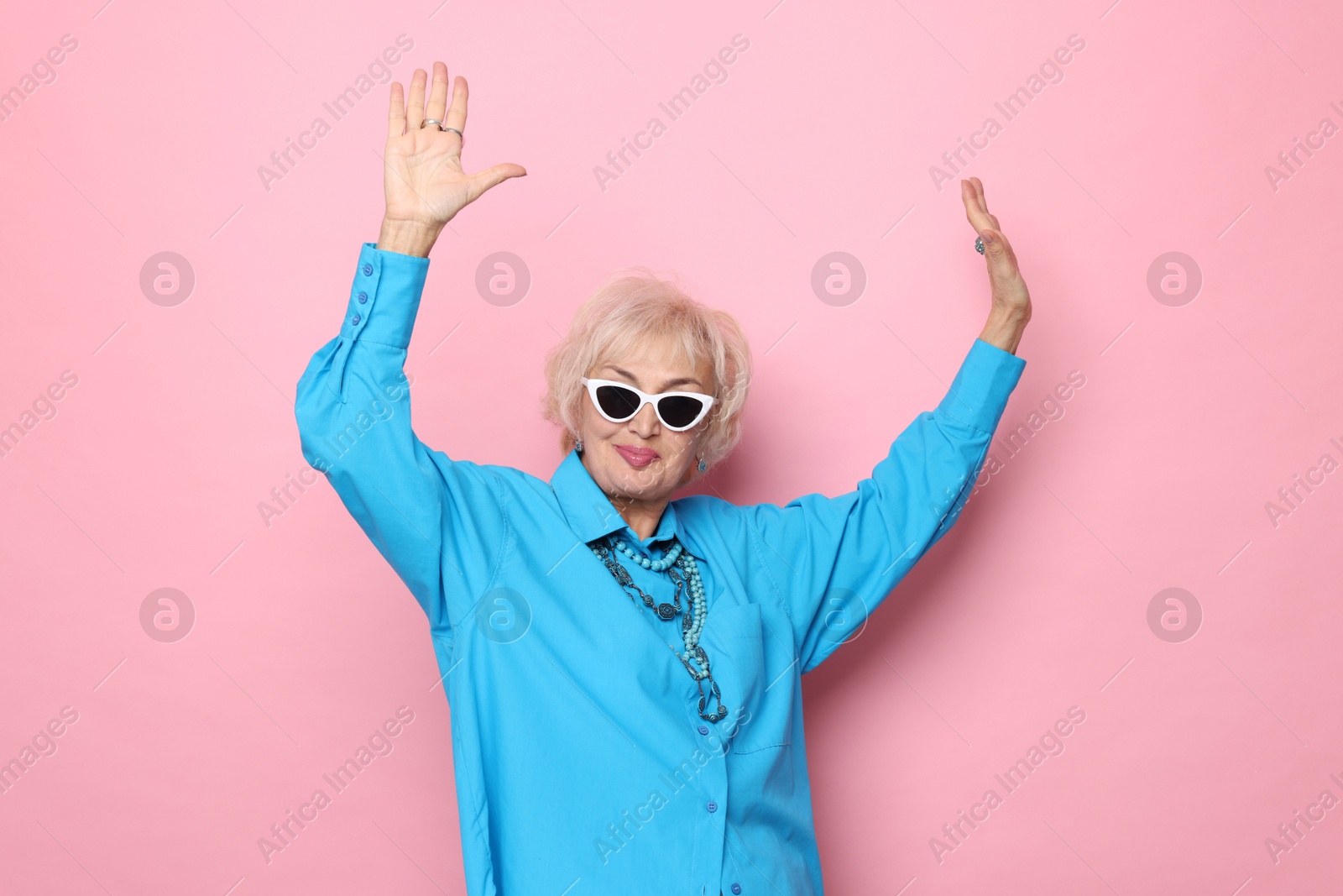 Photo of Portrait of cool grandmother in sunglasses on pink background