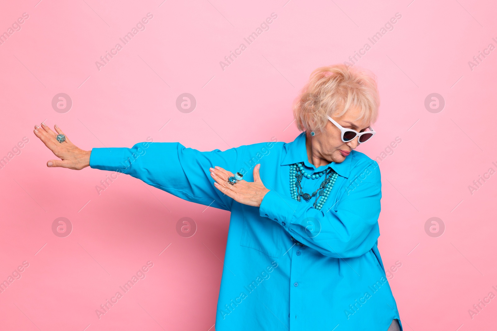 Photo of Portrait of cool grandmother in sunglasses on pink background