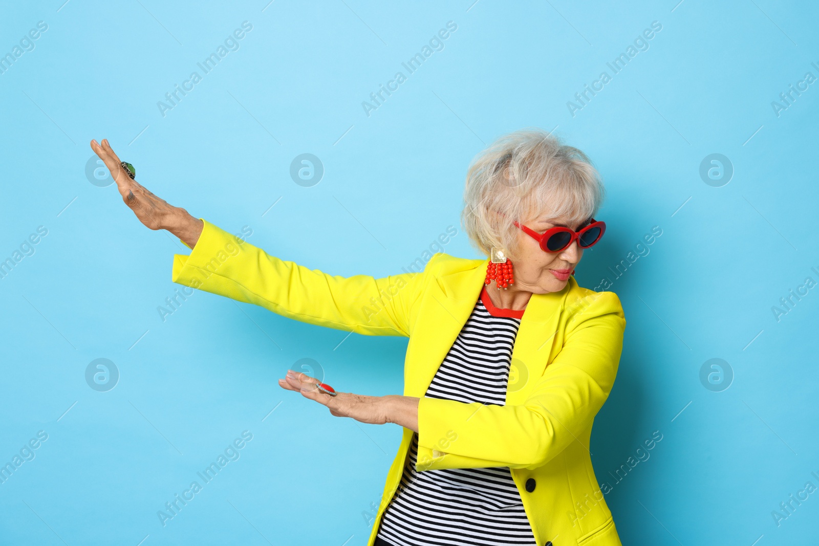 Photo of Portrait of cool grandmother in yellow jacket on light blue background