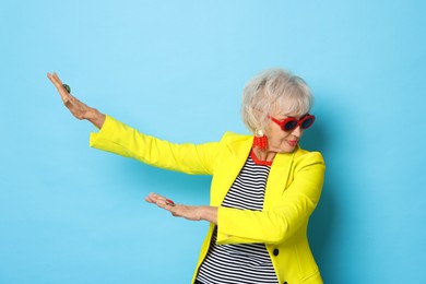 Photo of Portrait of cool grandmother in yellow jacket on light blue background