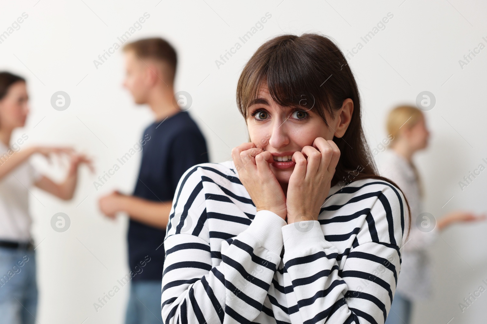 Photo of Young woman feeling uncomfortable among people indoors, selective focus