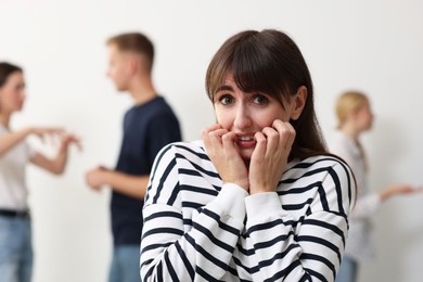 Young woman feeling uncomfortable among people indoors, selective focus