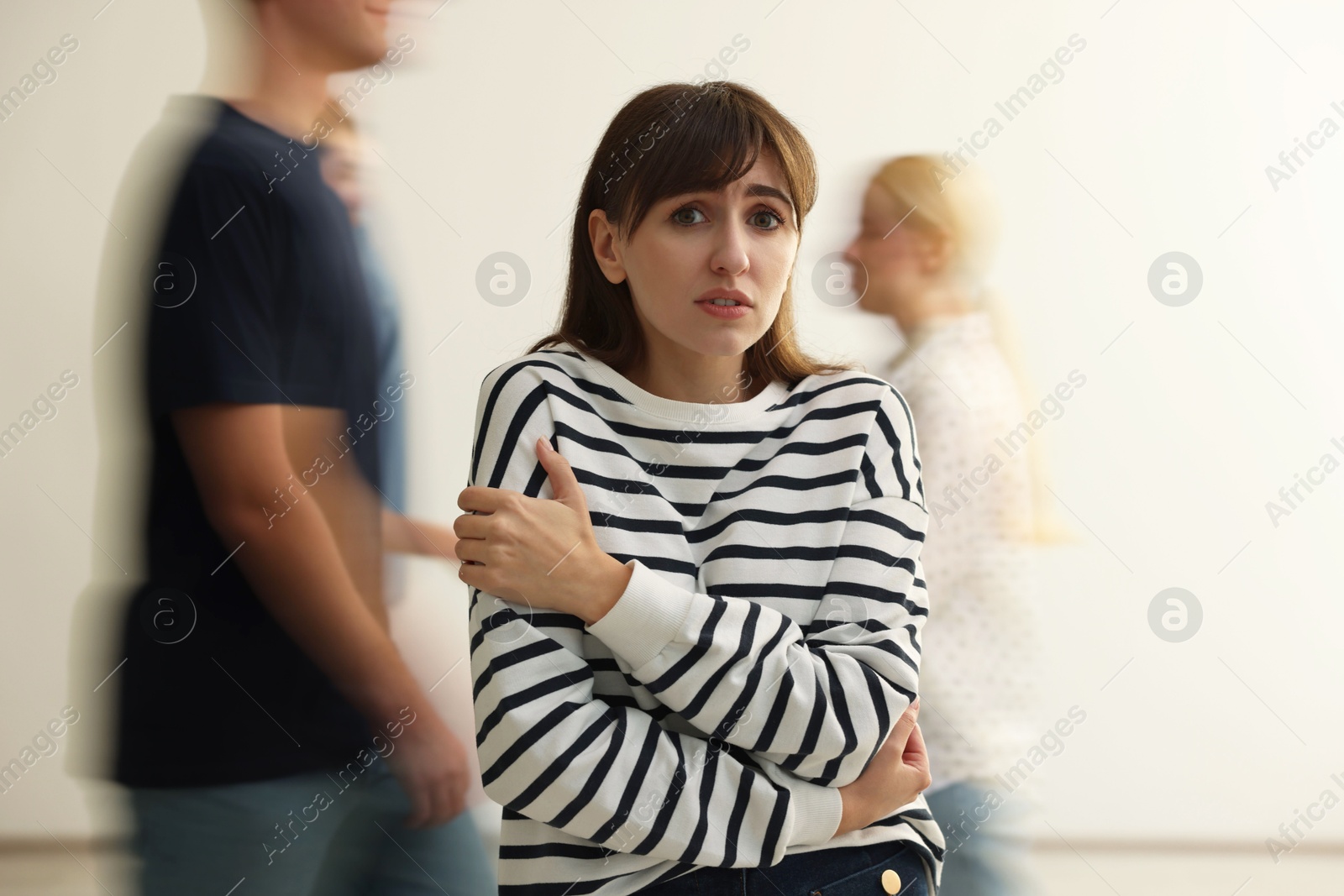 Photo of Young woman feeling uncomfortable among people indoors