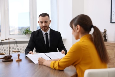 Photo of Client signing notarial paperwork during meeting with lawyer at wooden desk indoors