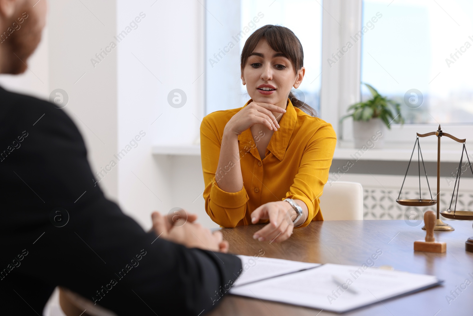 Photo of Woman having meeting with professional lawyer at wooden desk indoors