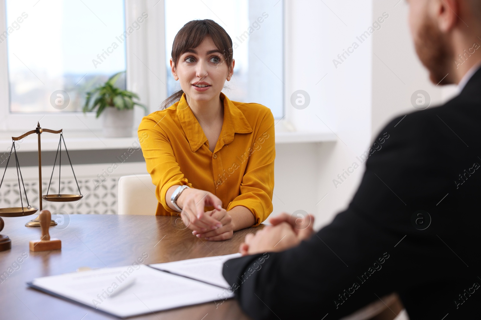 Photo of Woman having meeting with professional lawyer at wooden desk indoors