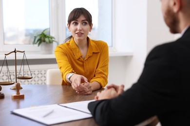 Woman having meeting with professional lawyer at wooden desk indoors