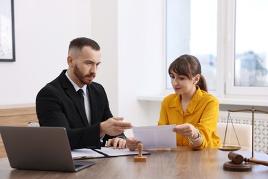 Photo of Woman having meeting with professional lawyer at wooden desk indoors