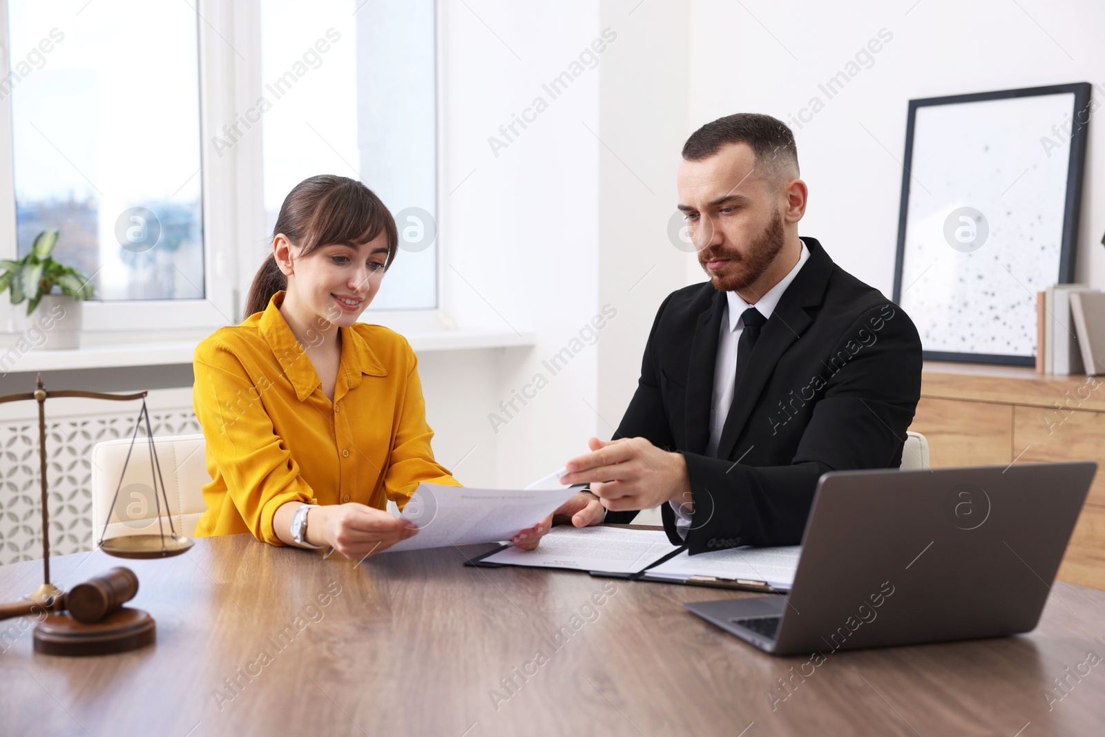 Photo of Woman having meeting with professional lawyer at wooden desk indoors