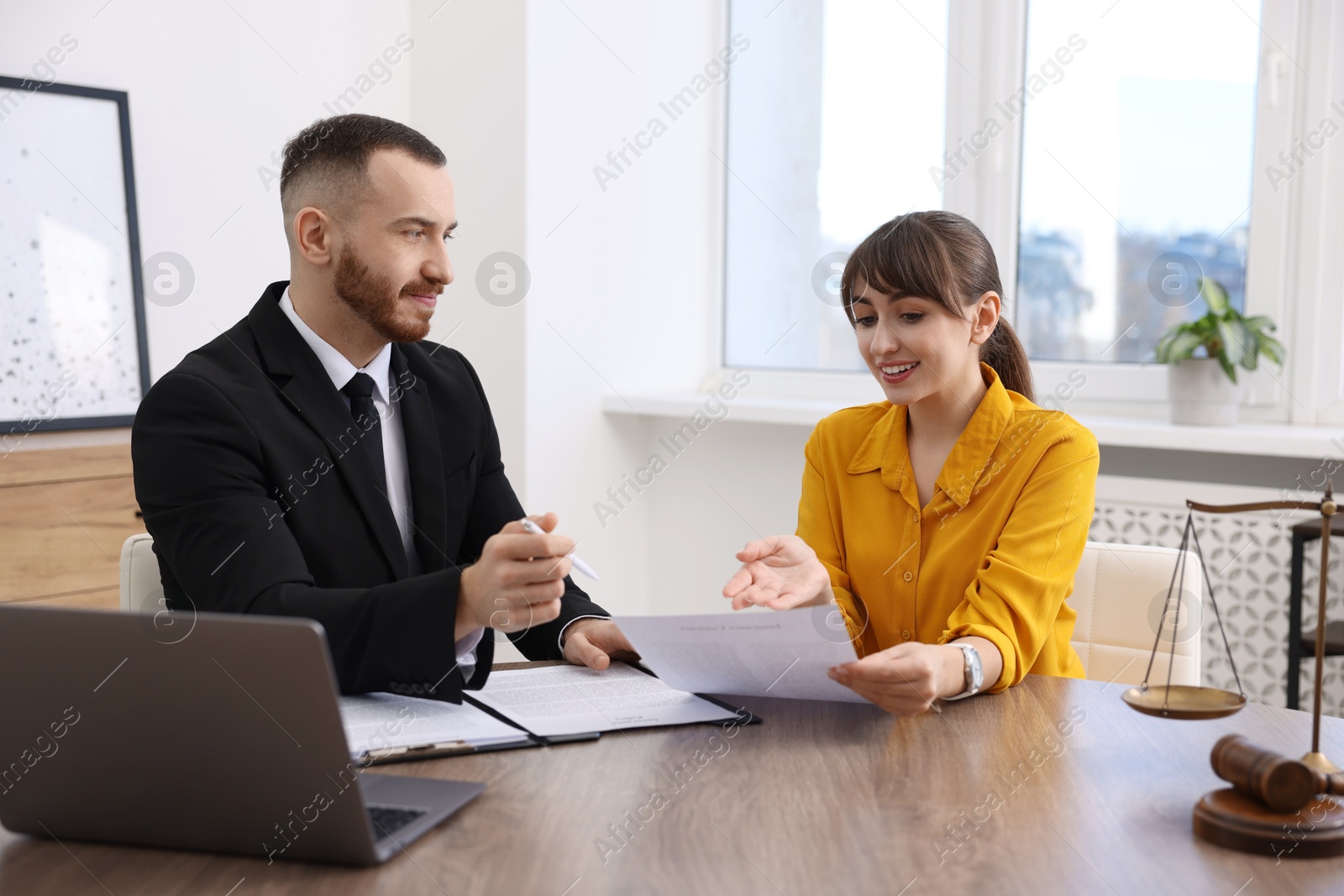 Photo of Woman having meeting with professional lawyer at wooden desk indoors