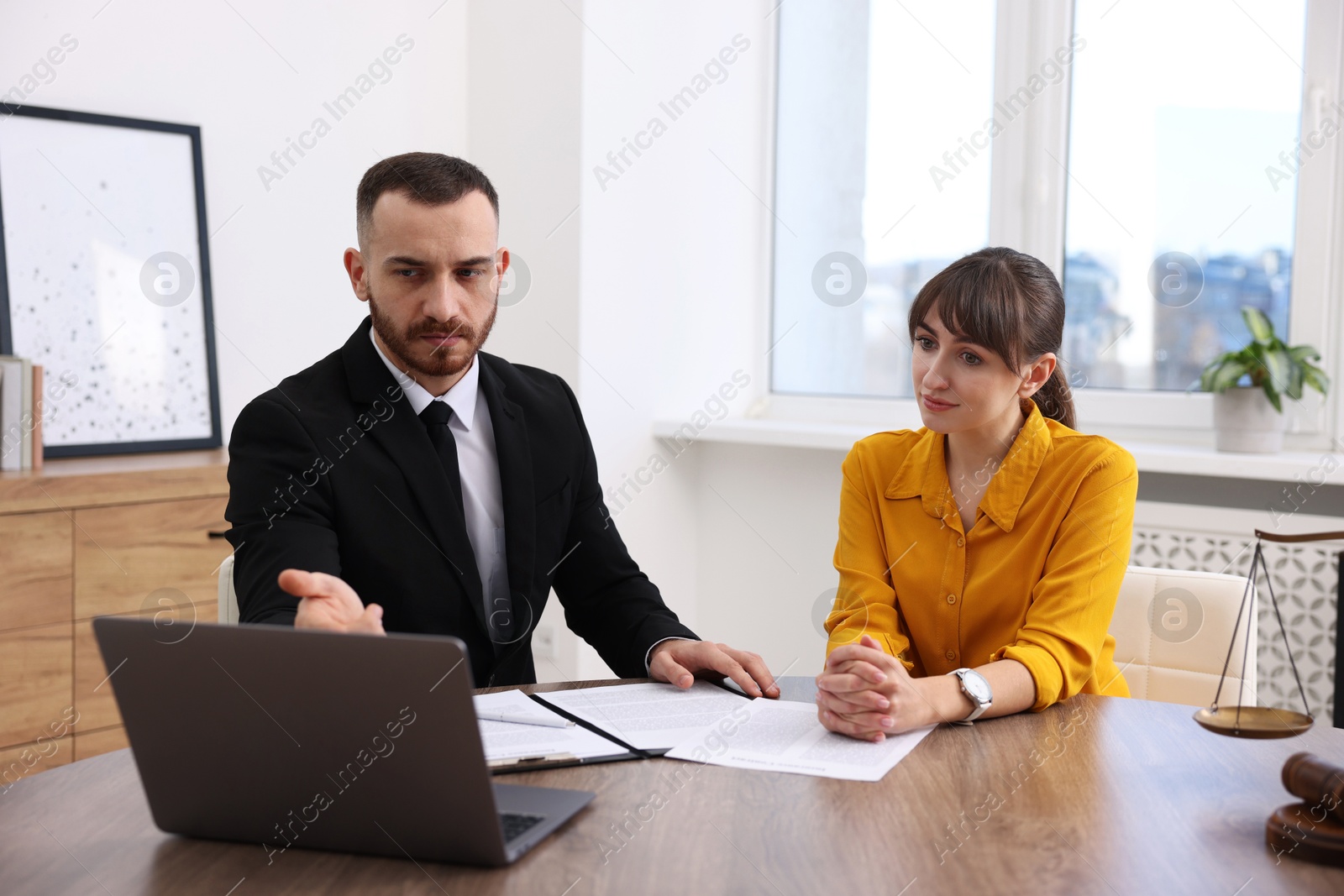 Photo of Woman having meeting with professional lawyer at wooden desk indoors