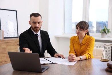 Photo of Woman having meeting with professional lawyer at wooden desk indoors