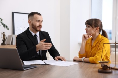 Photo of Woman having meeting with professional lawyer at wooden desk indoors