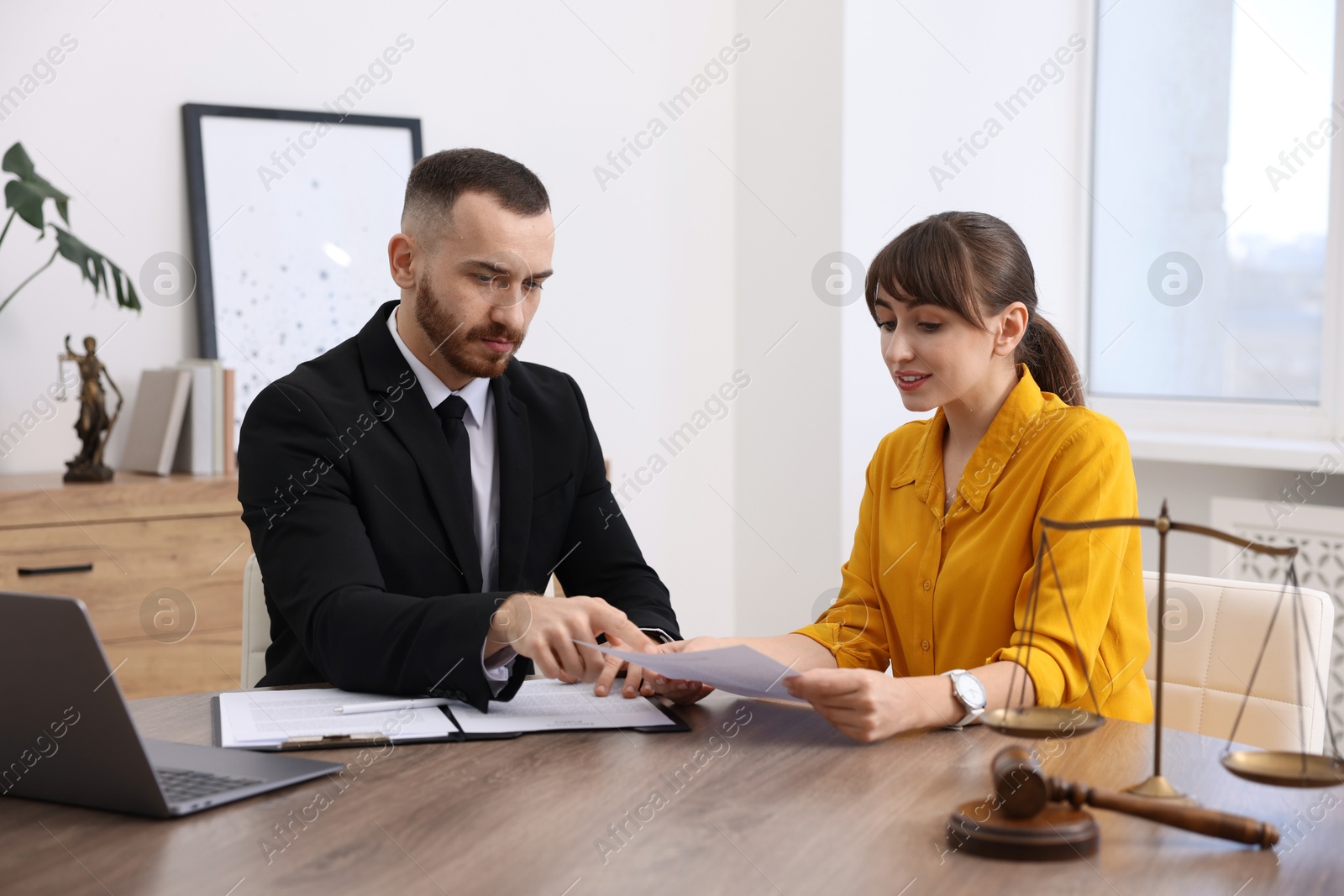 Photo of Woman having meeting with professional lawyer at wooden desk indoors