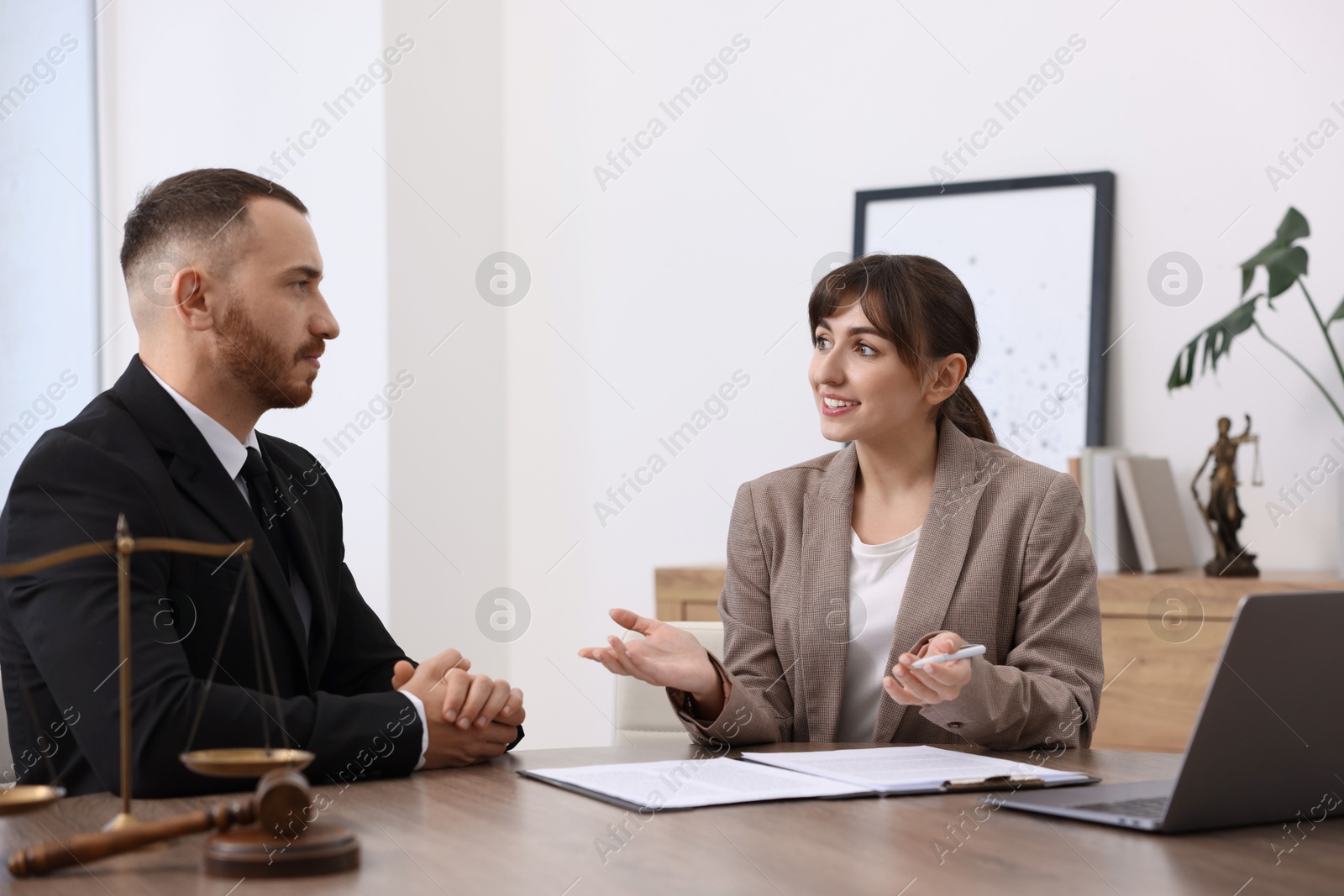 Photo of Man having meeting with professional notary at wooden desk indoors