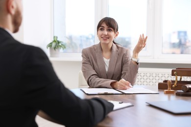 Photo of Man having meeting with professional notary at wooden desk indoors