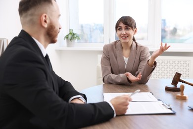 Photo of Client signing notarial paperwork during meeting with lawyer at wooden desk indoors, selective focus