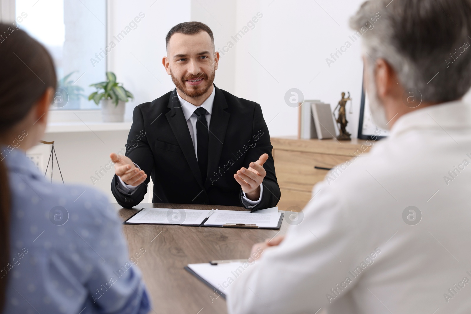 Photo of Man and woman having meeting with professional notary at wooden desk indoors