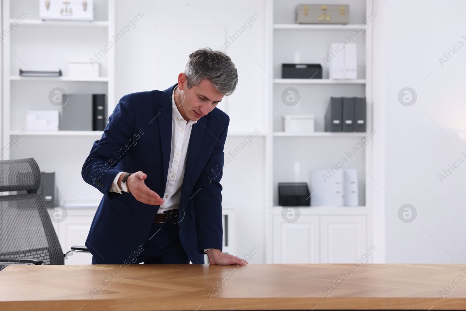 Photo of Man pointing at something on desk in office. Space for text