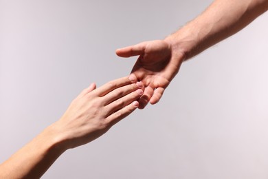 Photo of Man offering helping hand to his friend on light grey background, closeup