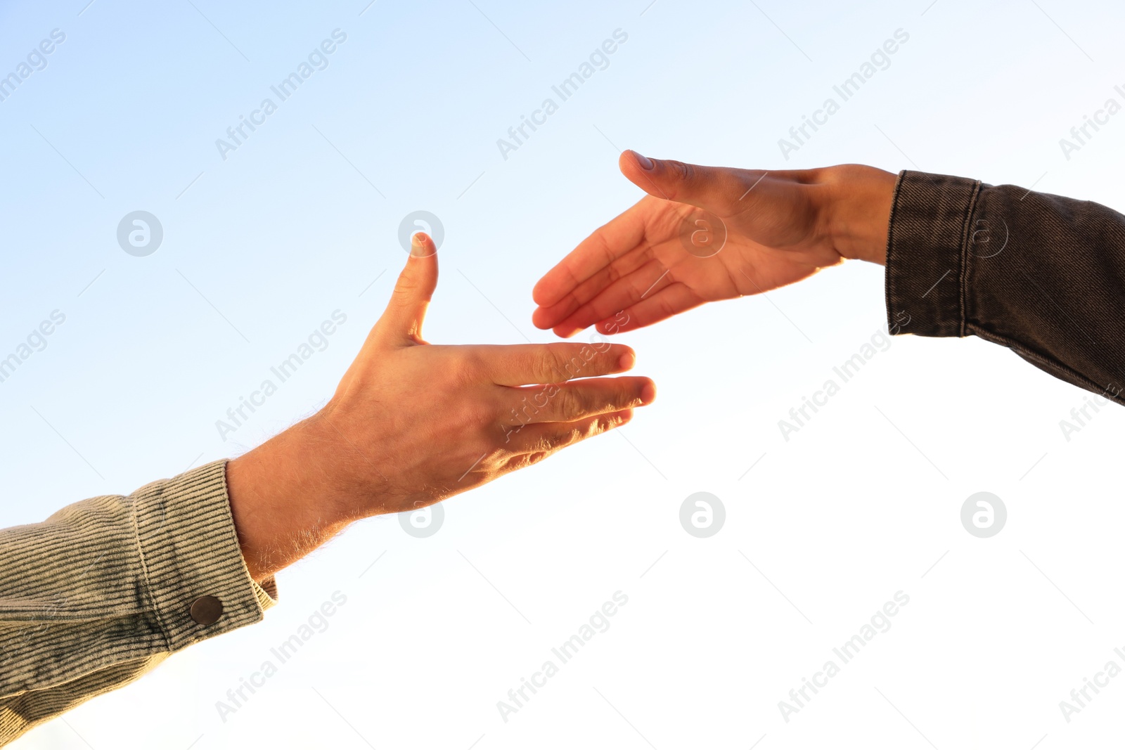 Photo of Man offering helping hand to his friend against blue sky, closeup