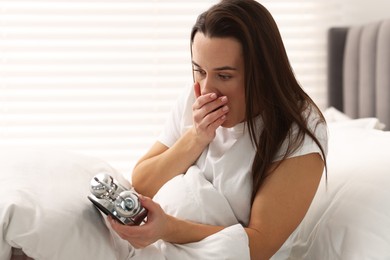 Photo of Overslept woman with alarm clock in bed at home