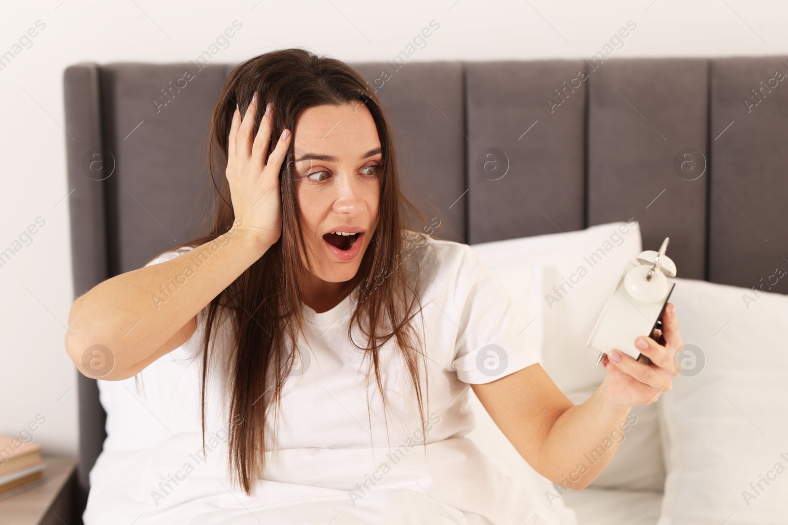 Photo of Overslept woman with alarm clock in bed at home