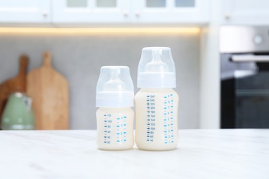 Photo of Feeding bottles with milk on white table indoors