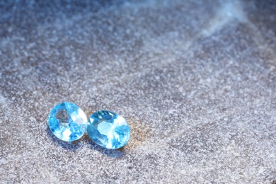 Photo of Beautiful shiny light blue gemstones on stone, space for text