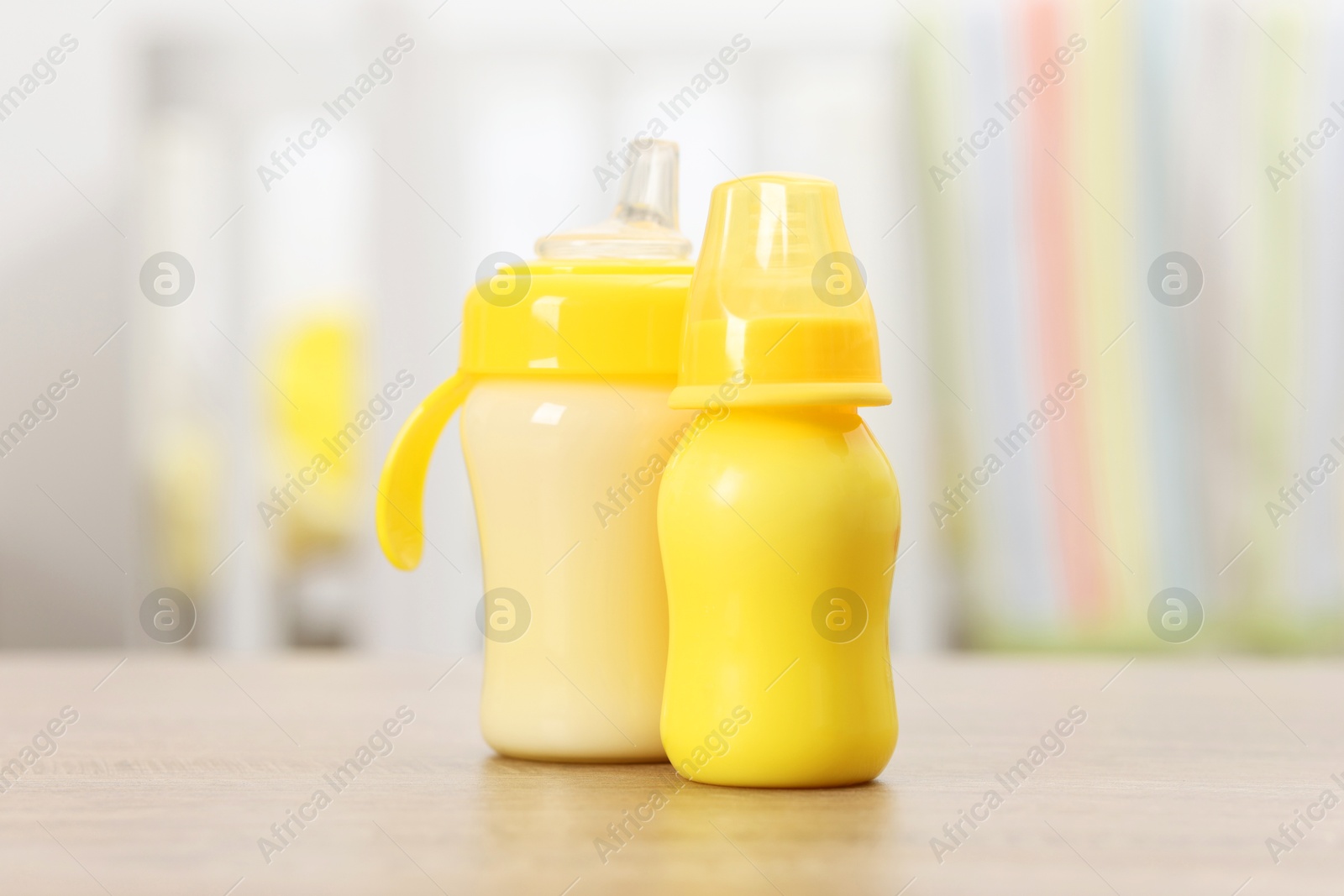 Photo of Feeding bottles with milk on wooden table indoors