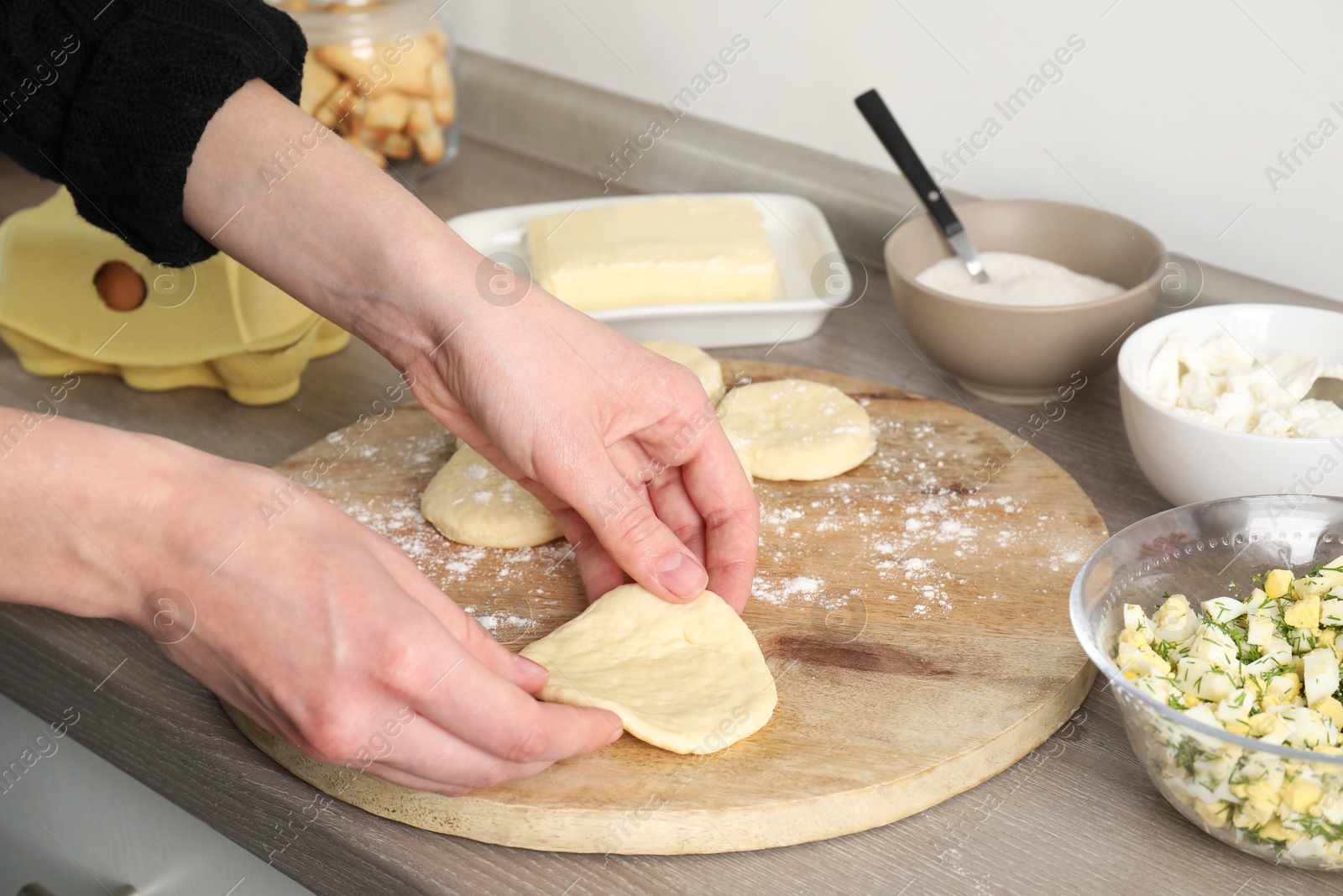 Photo of Woman making pirozhki (stuffed pastry pies) at countertop indoors, closeup