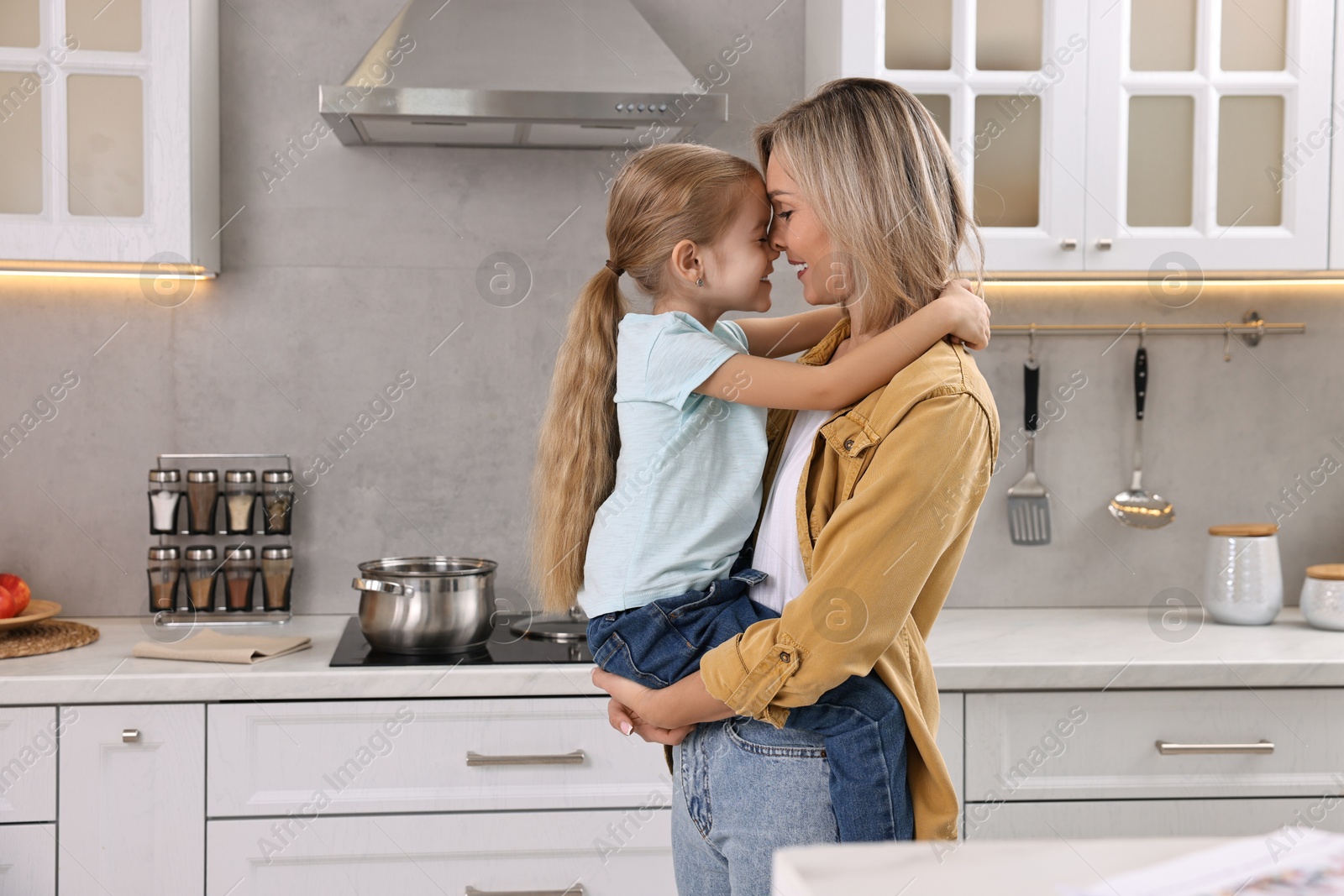 Photo of Happy housewife and her daughter cooking and spending time together in kitchen