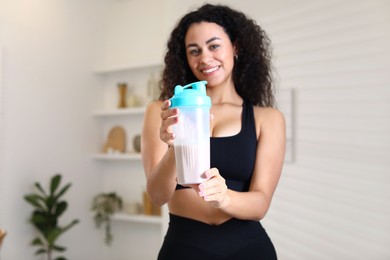 Photo of Beautiful woman with protein shake at home, selective focus