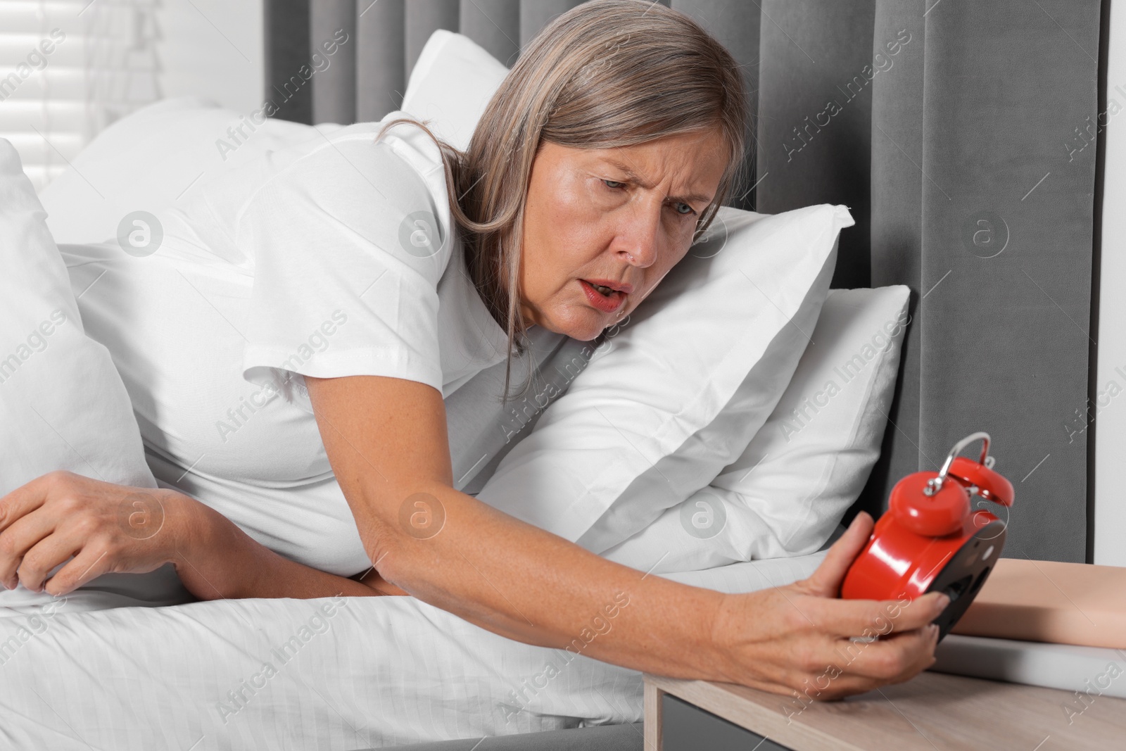 Photo of Overslept woman with alarm clock in bed at home