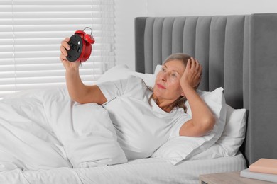 Photo of Overslept woman with alarm clock in bed at home