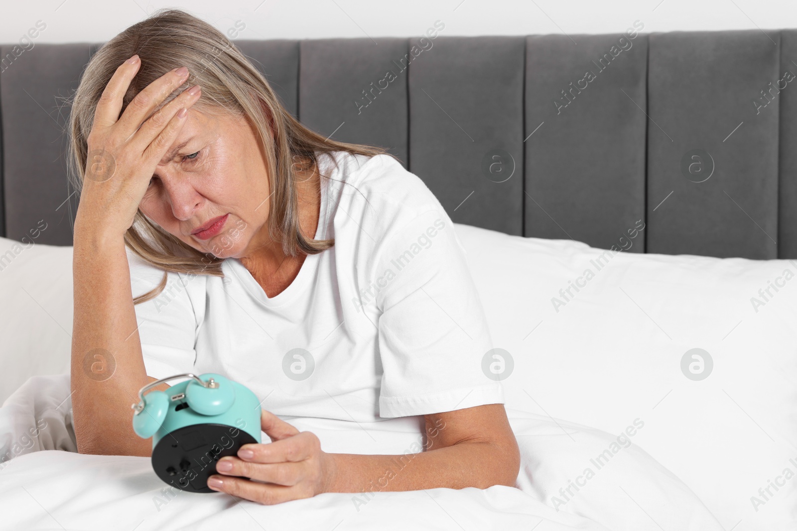 Photo of Overslept woman with alarm clock in bed at home. Space for text