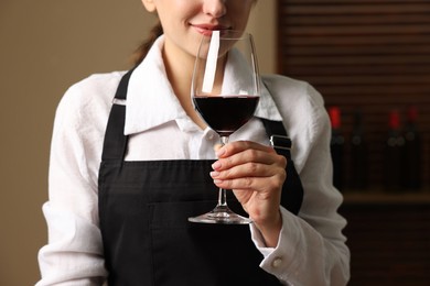 Professional sommelier tasting red wine in glass indoors, closeup