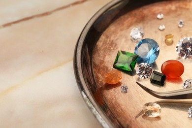 Photo of Tray with beautiful gemstones and tweezers on light table, closeup. Space for text